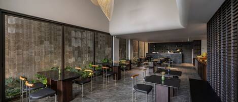 Restaurante moderno com móveis de madeira escura, um bar central e parede com padrão.