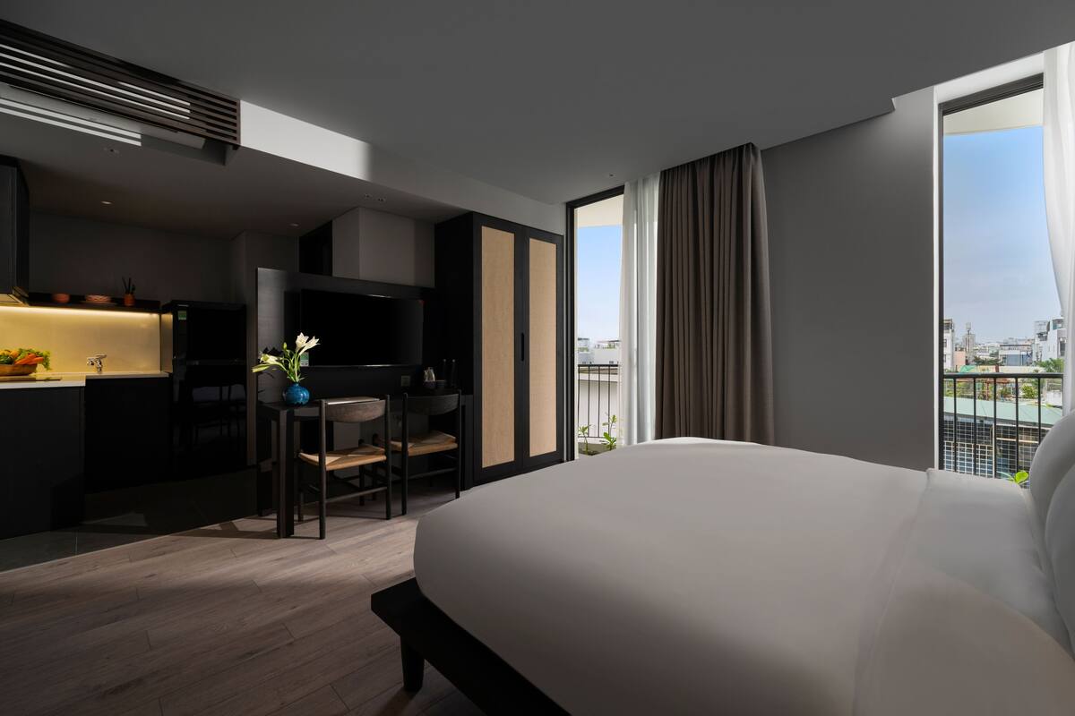 Une chambre d’hôtel moderne équipée d’un grand lit, d’un bureau et d’une kitchenette.