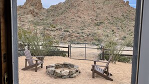 Une vue sur un paysage montagneux avec deux fauteuils Adirondack en bois et un foyer en pierre.