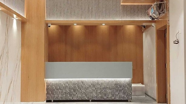 Een modern ingerichte receptie met een wand van houten panelen, een bank en een marmeren vloer.