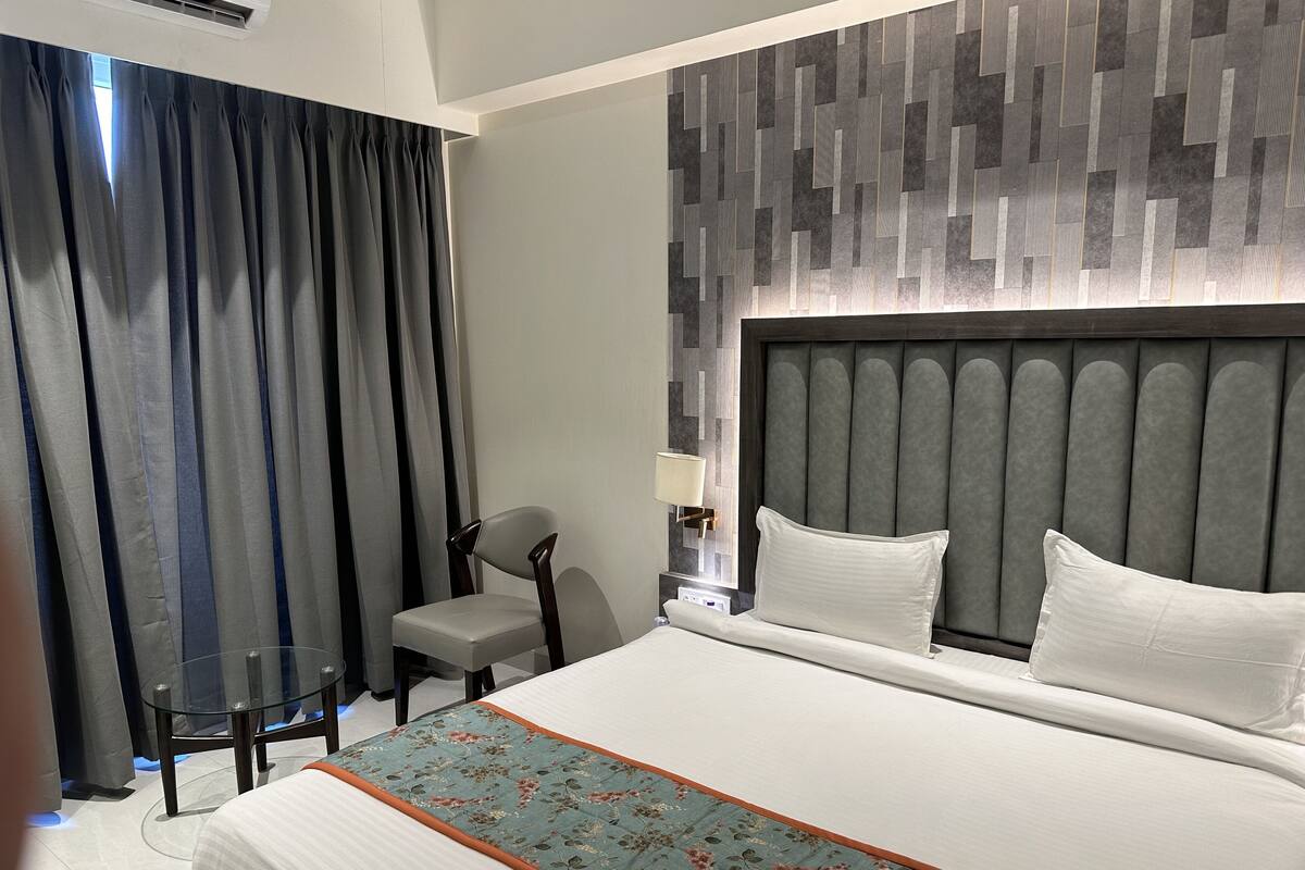 Hotellihuone, jossa on suuri sänky, tuoli, yöpöytä ja seinä, jossa on geometrinen kuvio.