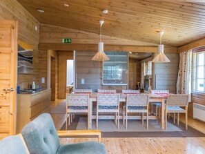 A wooden cabin interior with a dining area, a kitchen, and a living space. - Metsäntupa by Interhome (Inari)