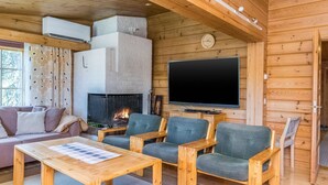 Interior acogedor de una cabaña con chimenea, televisor de pantalla plana, muebles de madera y un sofá.