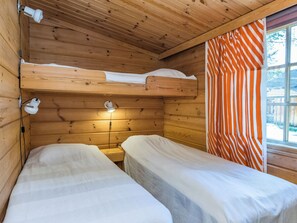 Une cabine équipée de deux lits superposés, d’une fenêtre avec des rideaux à rayures et d’une lampe fixée au mur.