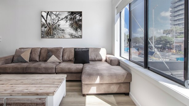 Ein modernes Wohnzimmer mit einem Ecksofa, einem Couchtisch und einem großen Fenster mit Blick auf die Stadt.