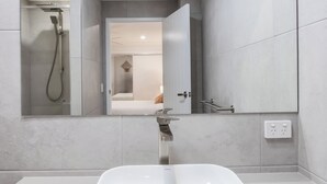 Ein modernes Badezimmer mit einer großen Badewanne, einer Dusche und einem Spiegel.