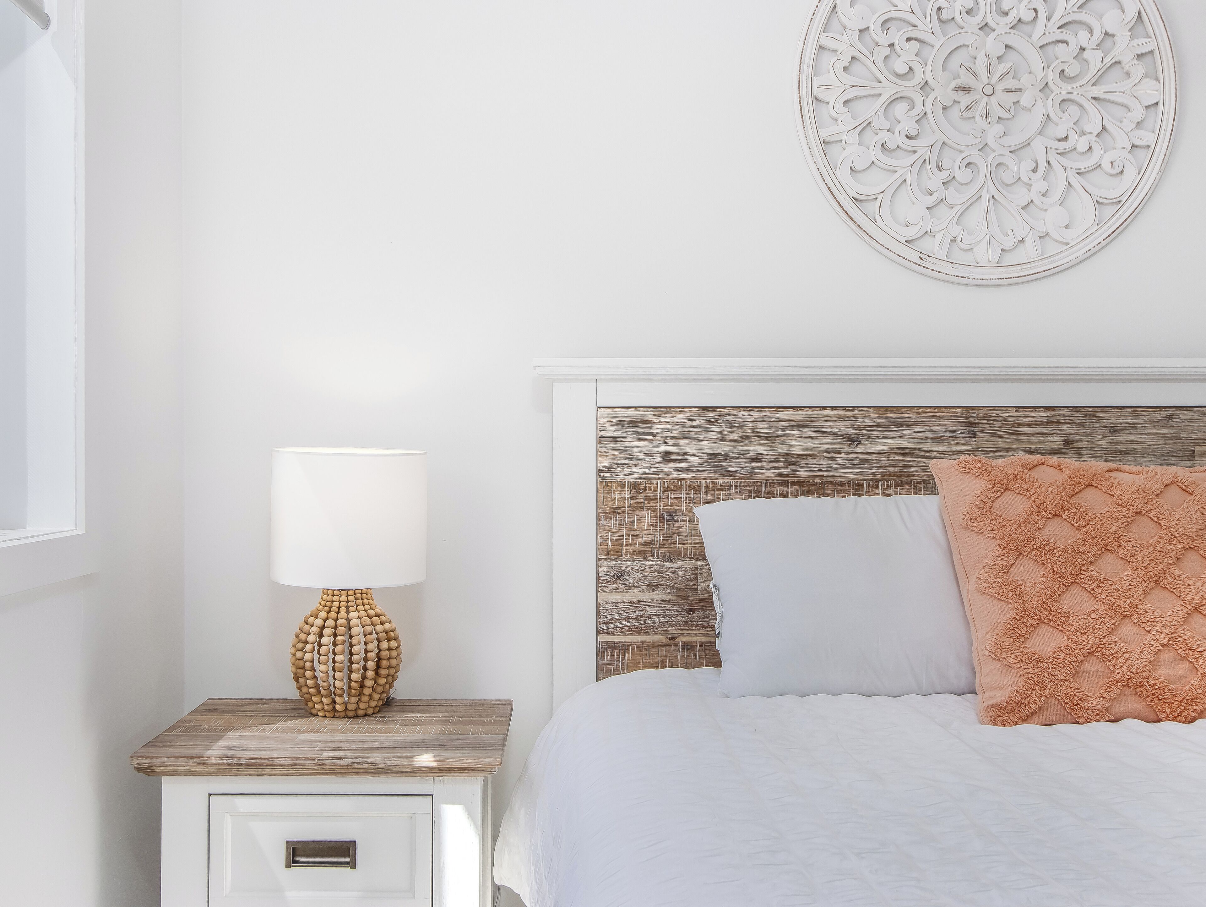 Un dormitorio ordenado con cabecera de madera, lámpara de noche y un adorno en la pared.