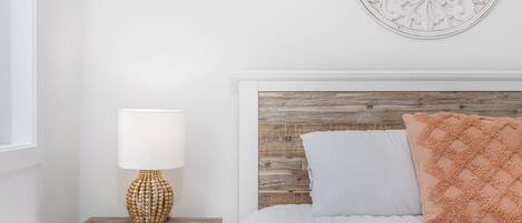 Un dormitorio ordenado con cabecera de madera, lámpara de noche y un adorno en la pared.