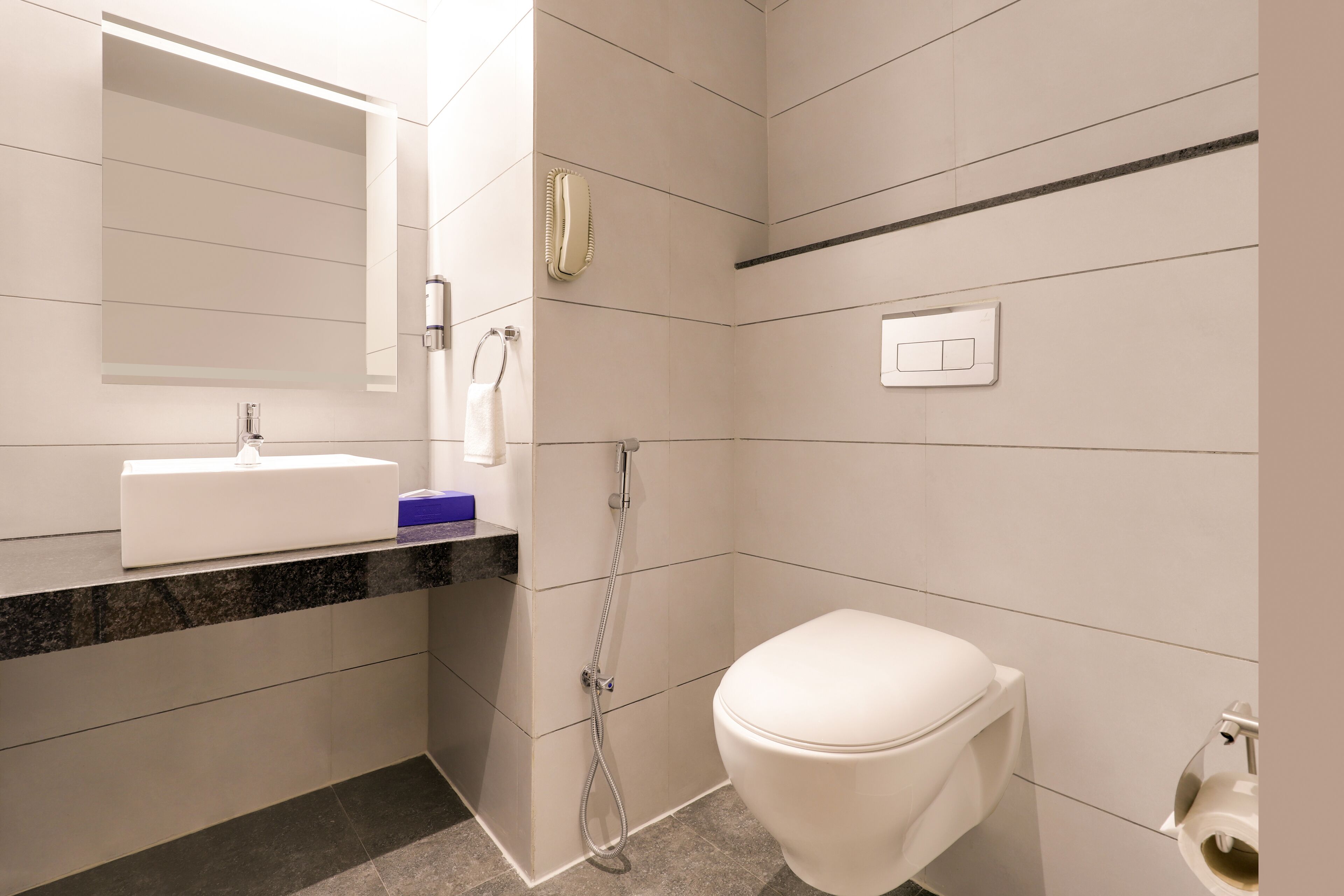 Un baño moderno con lavamanos, espejo y retrete blancos.