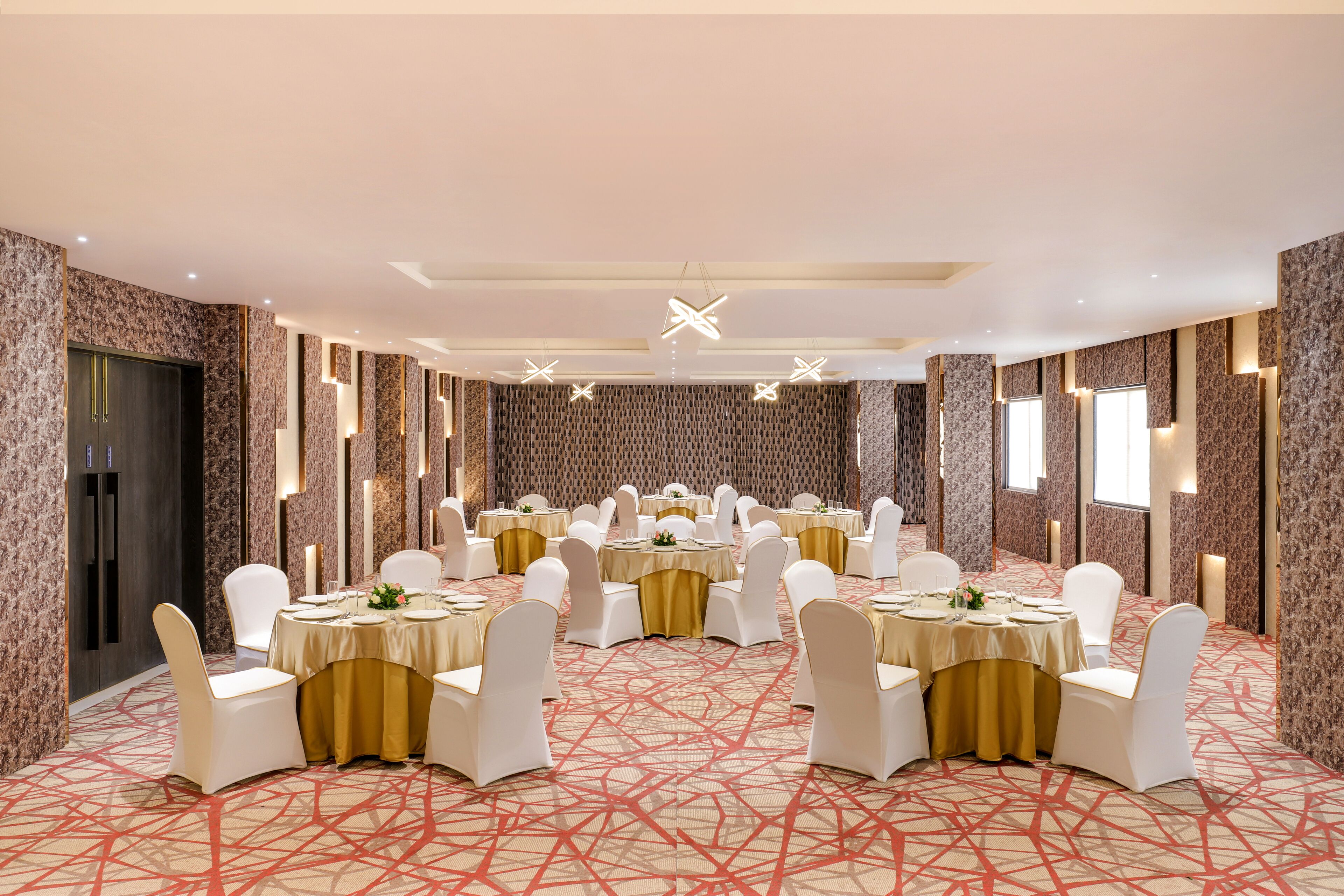 A banquet hall with round tables, white chairs, and gold sashes.