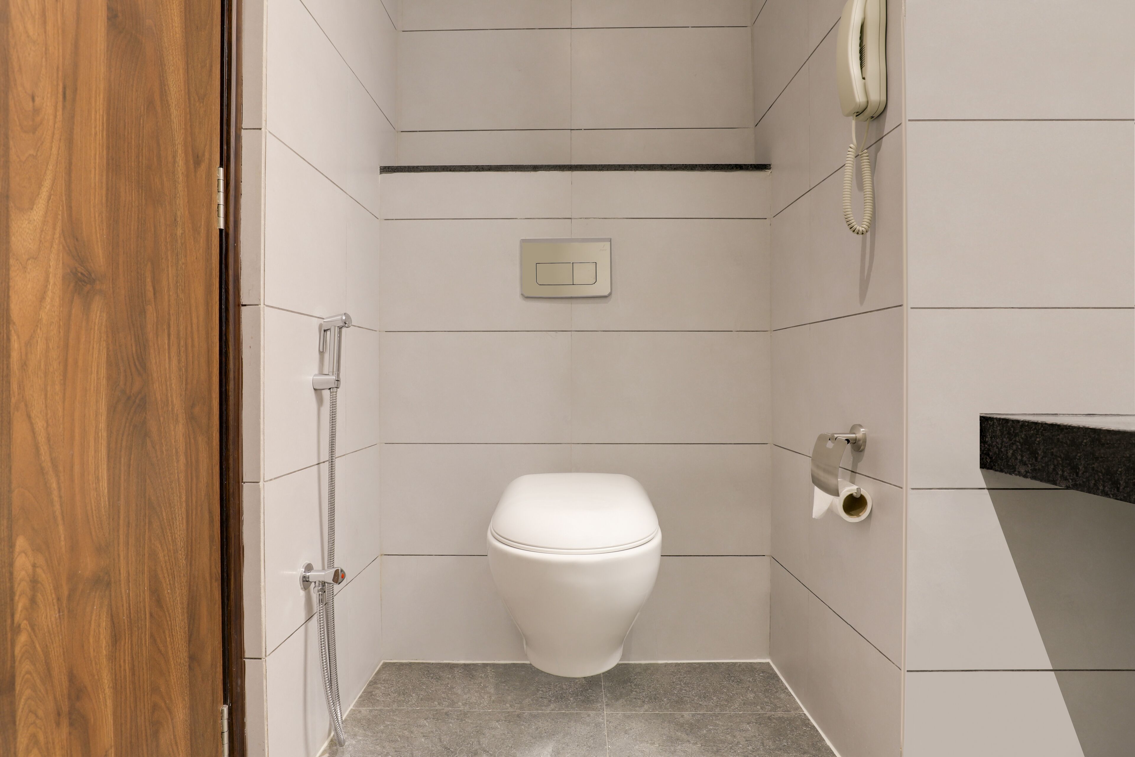 Un baño pequeño y moderno con inodoro, ducha y teléfono.