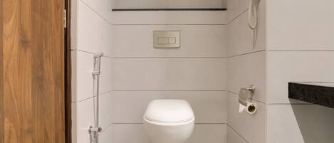 Un baño pequeño y moderno con inodoro, ducha y teléfono.
