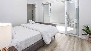 A modern bedroom with a bed, a bedside table, a wardrobe, and a sliding glass door leading to a balcony. - 3 Bedroom Beachside Haven in Burleigh Heads (Gold Coast)
