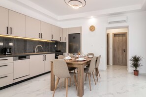Une cuisine moderne avec un coin repas. Elle comprend un évier, une cuisinière et des placards. On y trouve une table à manger avec des chaises et une horloge au mur.