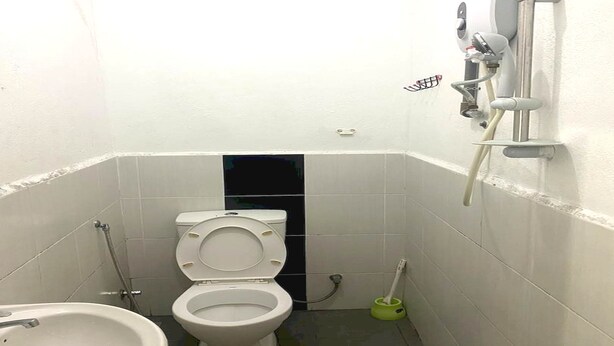 A small, white bathroom with a toilet, bidet, and a green brush. - OYO 90935 Langkawi Western Motel (Langkawi)