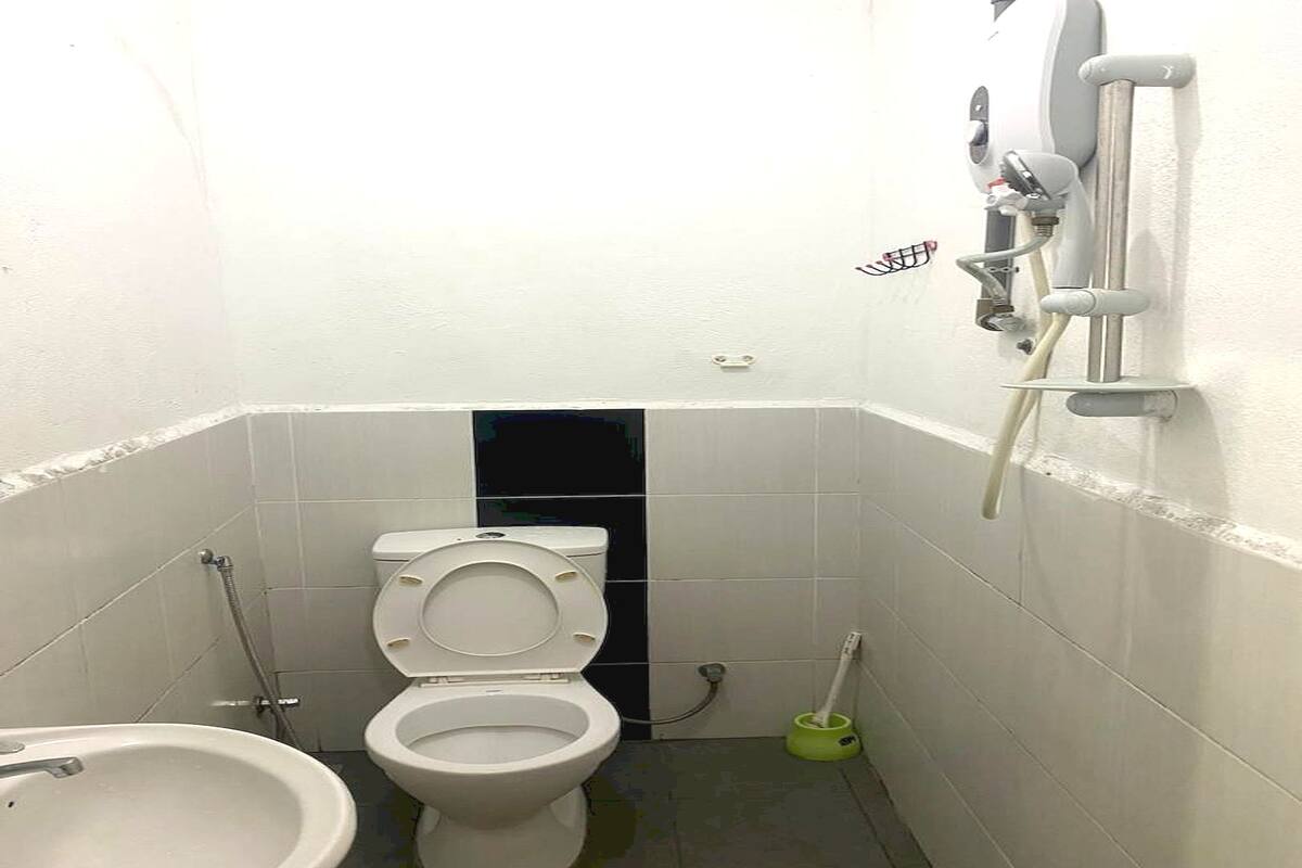 Un baño pequeño y blanco con inodoro, bidé y un cepillo verde.