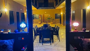 A spacious dining area with a high ceiling and a central table surrounded by chairs. - Ryad Marocain Proche D'agadir 15 Personnes - 6 Chambres - 3 sdb - 1 Piscine (Ifentar)