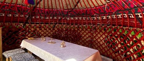 A traditional yurt with a white table and benches, decorated with colorful tassels.
