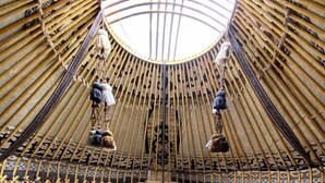 A yurt-style room with a central bed, two benches, and a hanging light fixture. - Kel-Suu At-Bashy (Kel Suu)