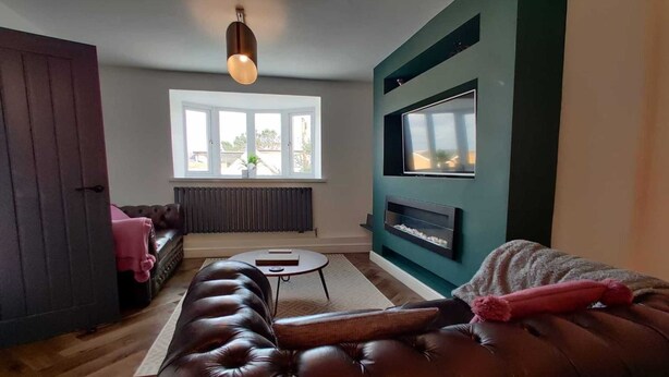 Ein modernes Wohnzimmer mit einer Ledersofa, einem kleinen runden Tisch, einem Kamin und einem großen Fenster.