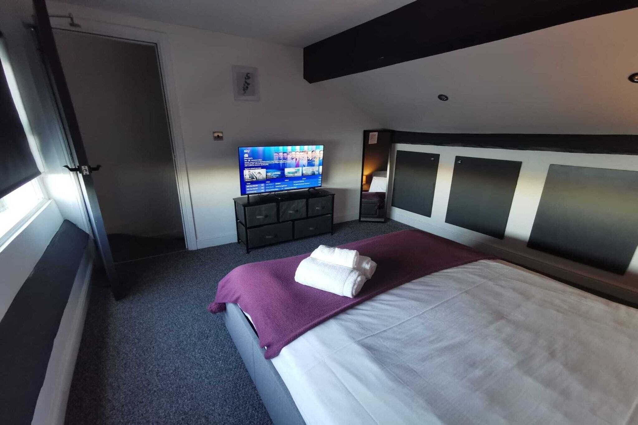 Une chambre d’hôtel avec un lit, une télévision, une commode et une porte.