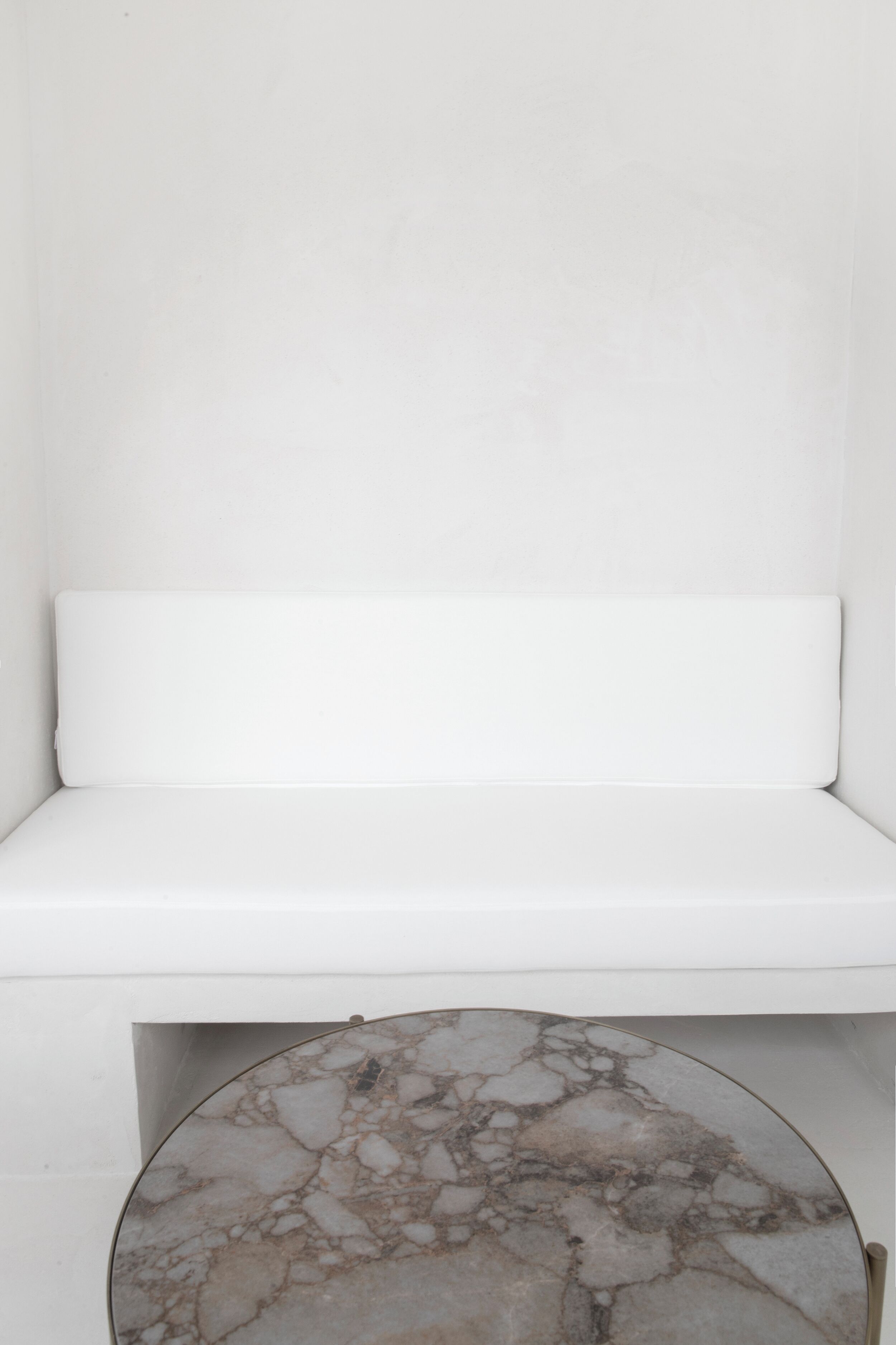 A white bench with a marble-topped table in front of it.