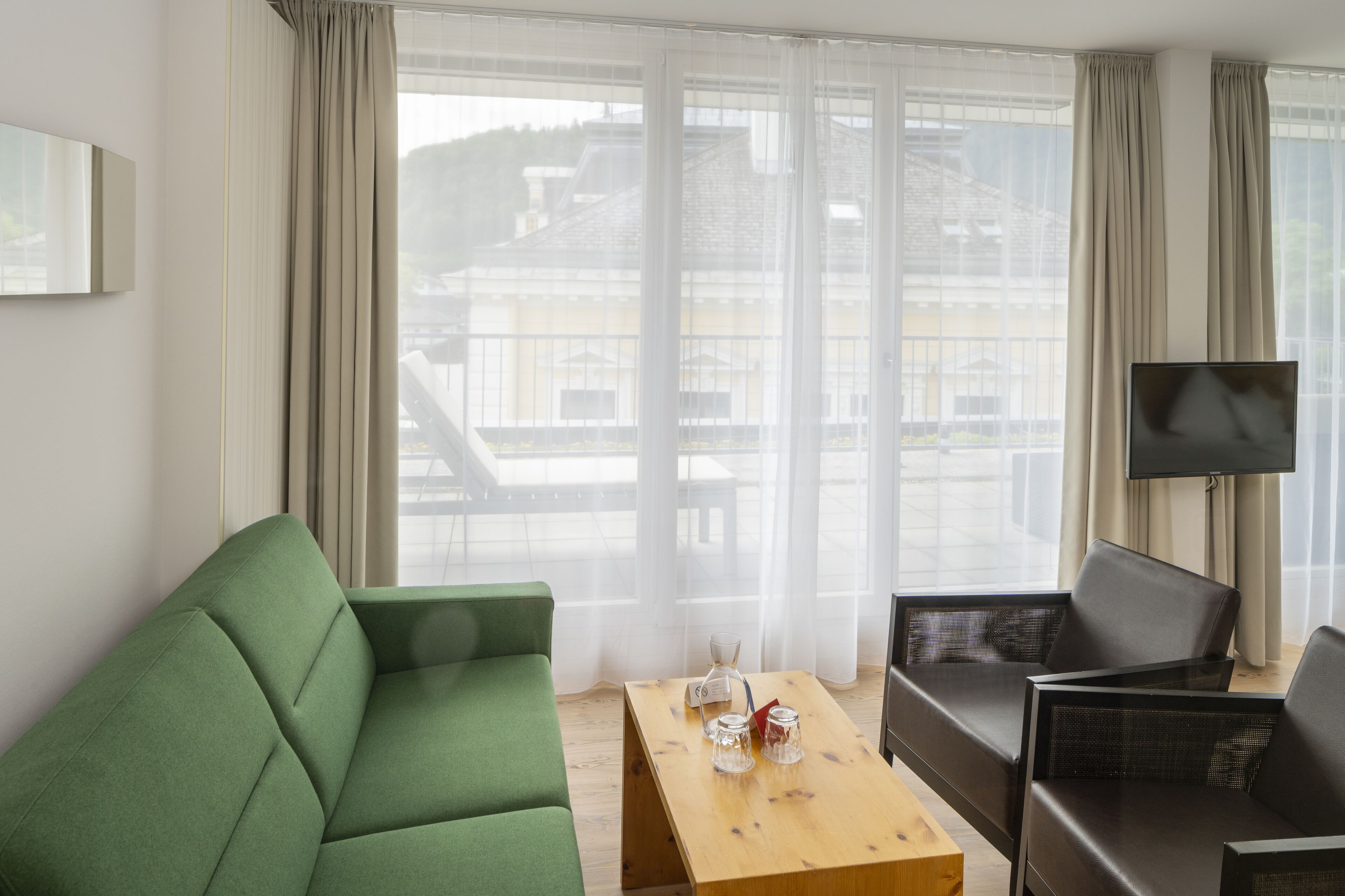 Un salon moderne avec un canapé vert, une table basse en bois et un canapé noir.