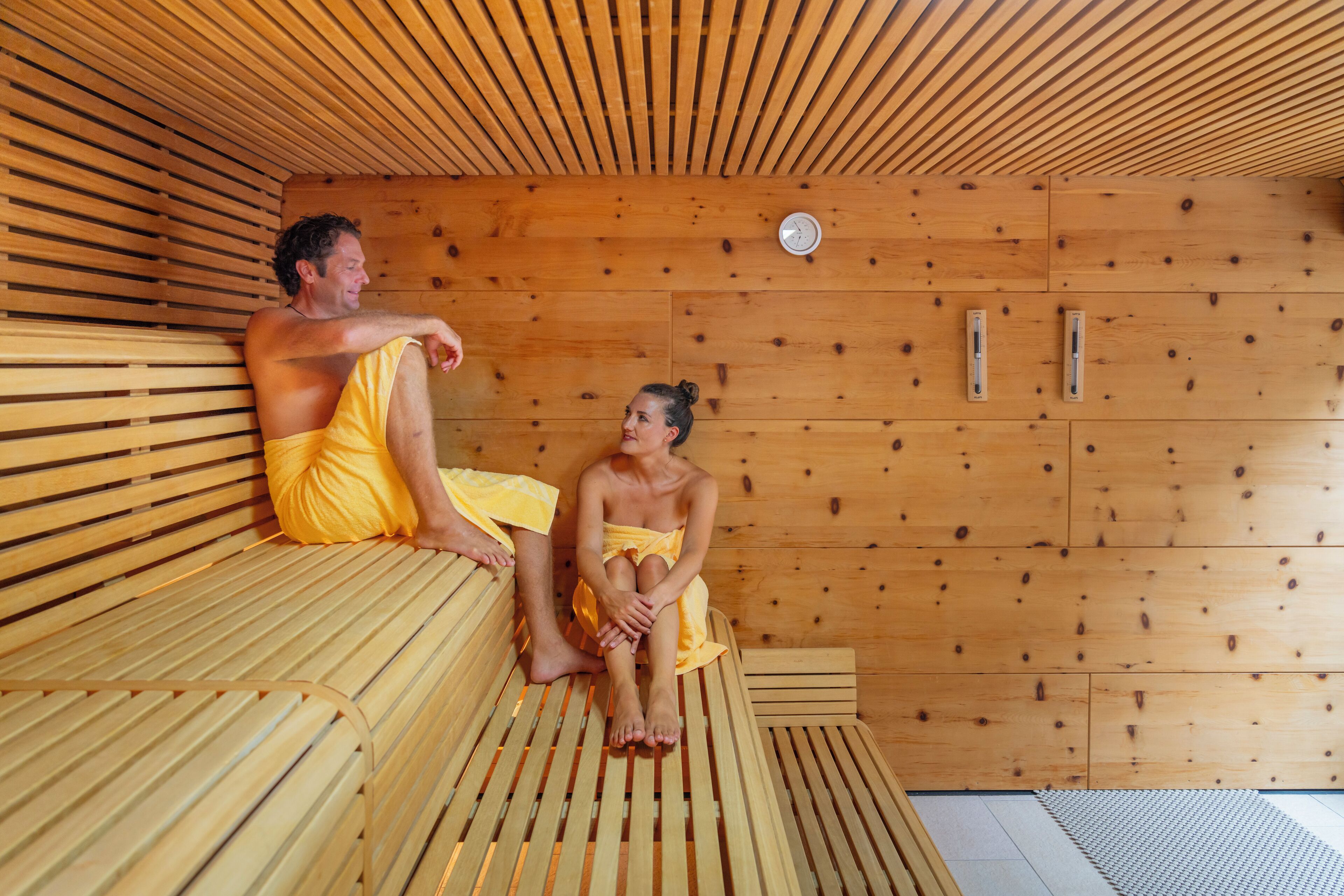 A wooden sauna with benches and a wall-mounted heater.