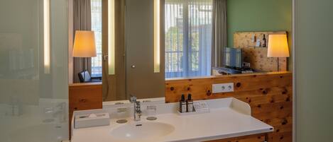 A modern bathroom with a white sink, wooden paneling, a large mirror, and two wall-mounted lamps.