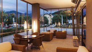 Une chambre d’hôtel moderne dotée de grandes fenêtres, de sièges confortables et offrant une vue sur le paysage urbain.