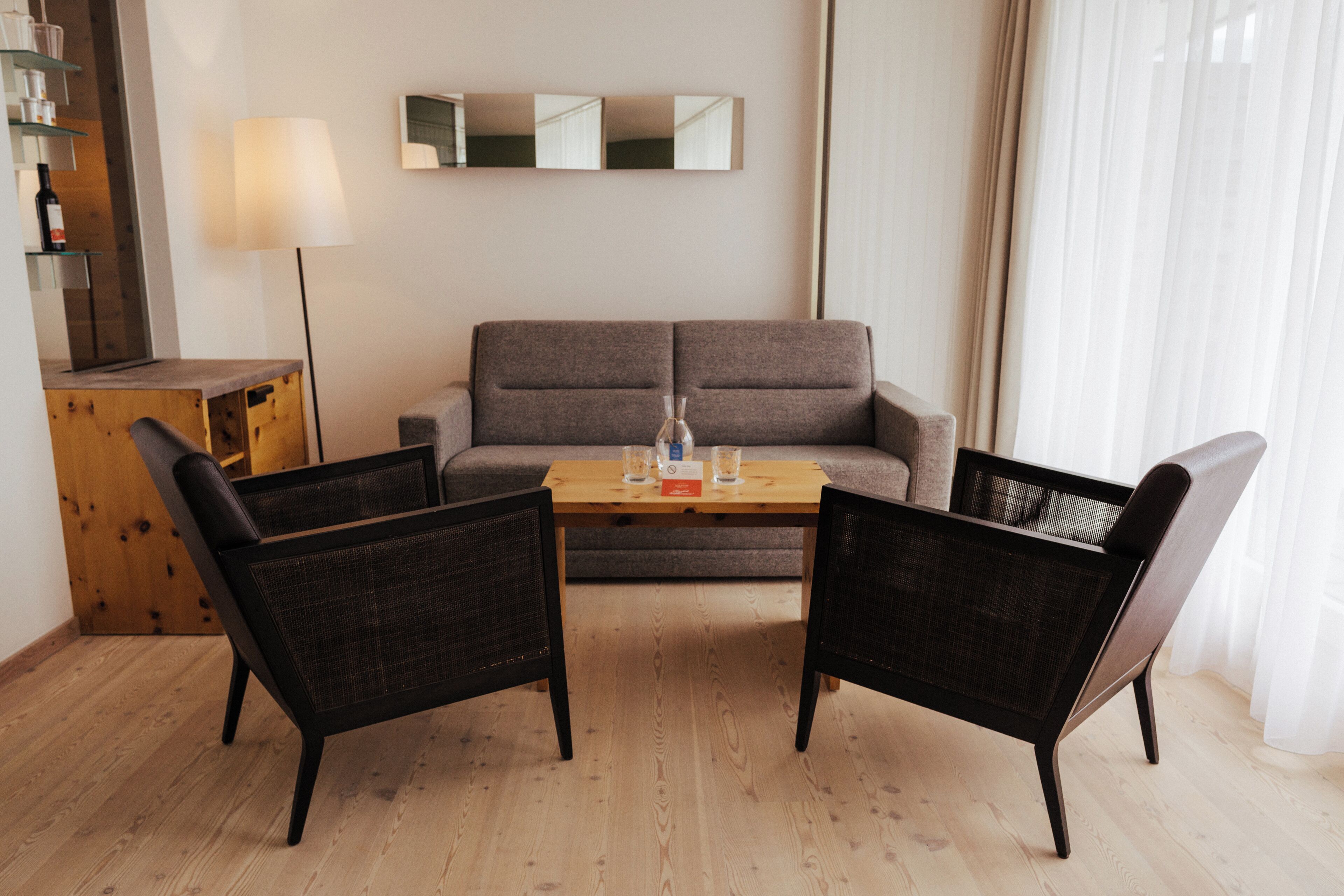 A modern living room with a sofa, two armchairs, a coffee table, and a lamp.