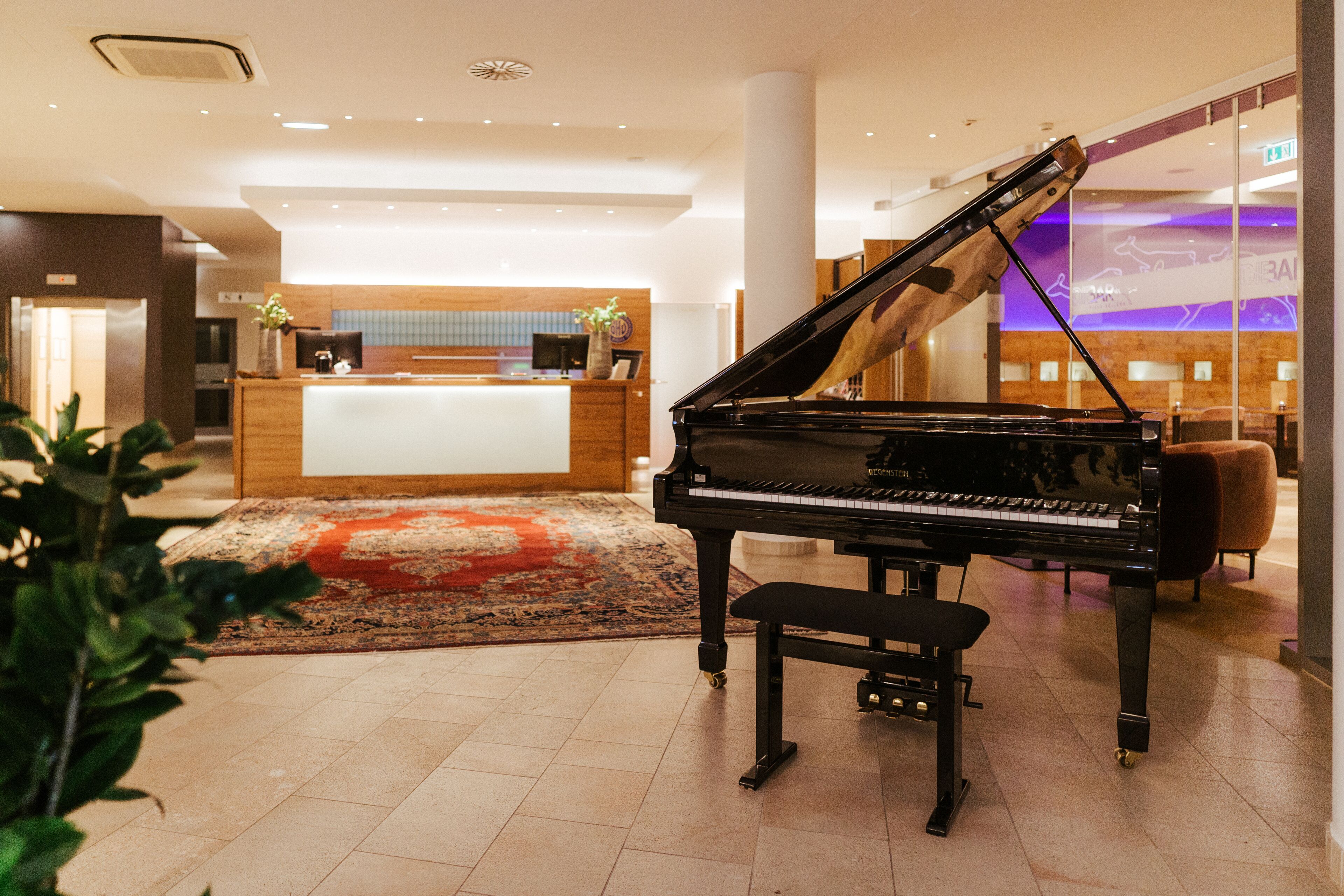 Un gran piano en un vestíbulo con mostrador de recepción, zona de recepción de madera y diseño interior moderno.
