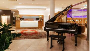 Un gran piano en un vestíbulo con mostrador de recepción, zona de recepción de madera y diseño interior moderno.