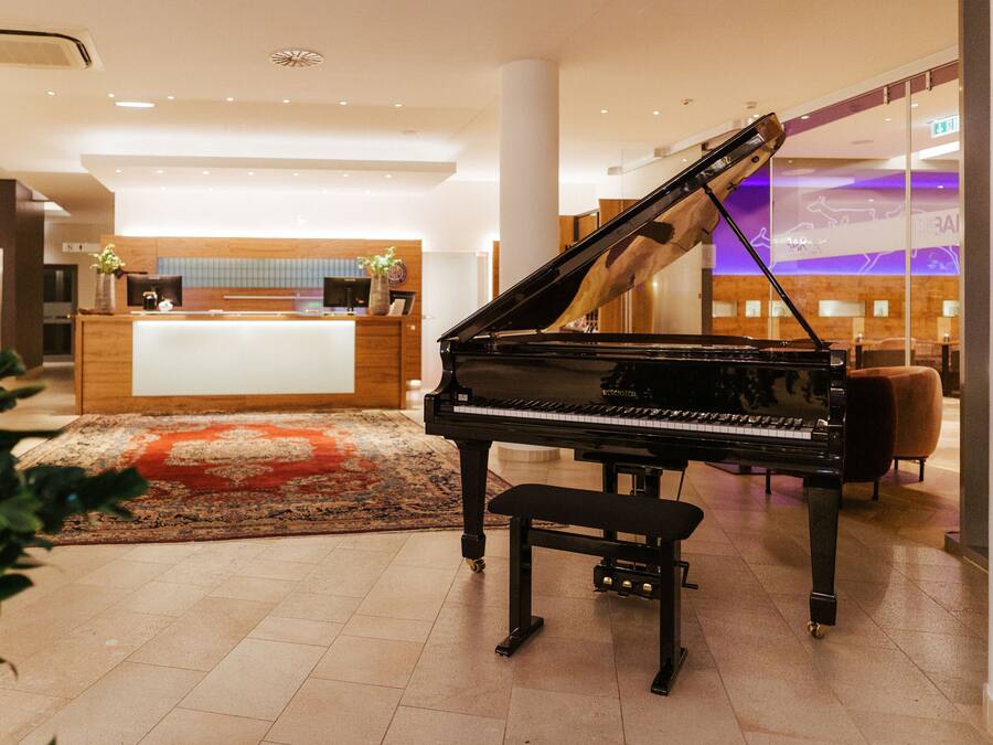 Un gran piano en un vestíbulo con mostrador de recepción, zona de recepción de madera y diseño interior moderno.