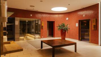 Relax in the inviting lobby, featuring a central table, lush greenery, and warm red accents.