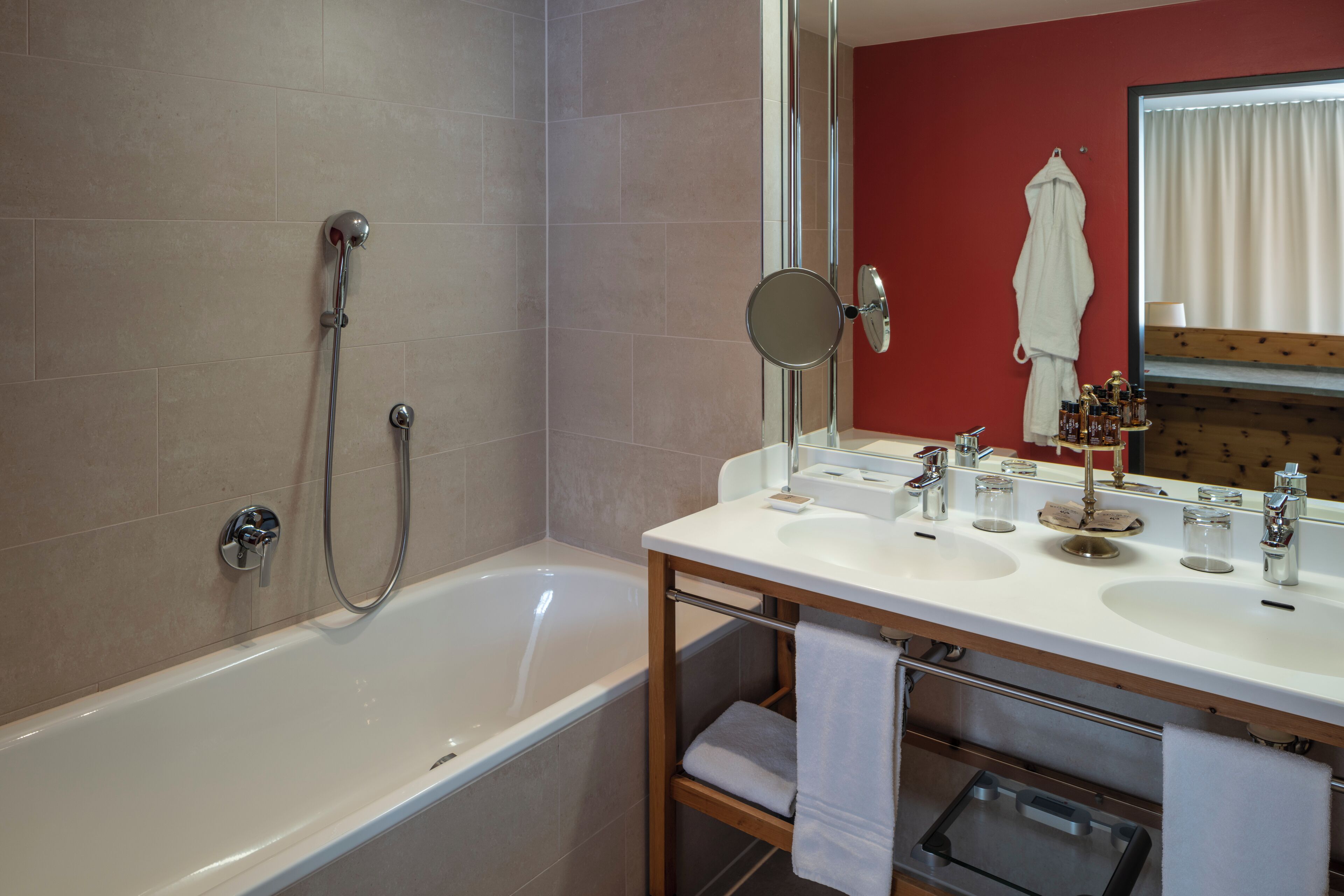 A modern bathroom with a bathtub, a vanity with two sinks, a mirror, and a towel rack.