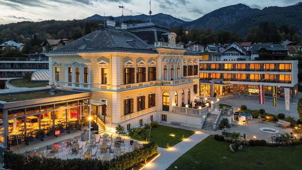 Un hôtel à la façade classique, doté d’un espace extérieur aménagé pour s’asseoir et d’un jardin bien entretenu.