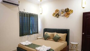 A neatly arranged hotel room with a bed, a small round table, a wall-mounted air conditioner, and a door. - HOTEL URBAN SLEEP (Hyderabad)