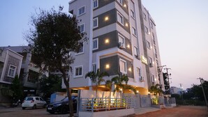 A multi-story residential building with balconies, a gated entrance, and a tree in front. - HOTEL URBAN SLEEP (Hyderabad)