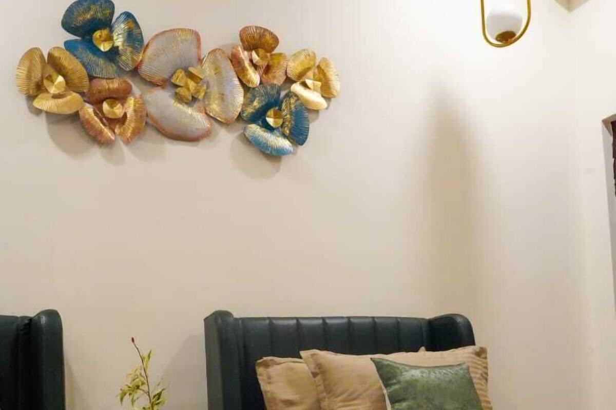 Habitación de hotel con dos camas, una mesita con una planta y un adorno en la pared.