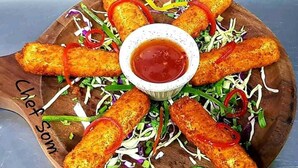 A wooden board with breaded items and a bowl of sauce. - HOTEL URBAN SLEEP (Hyderabad)