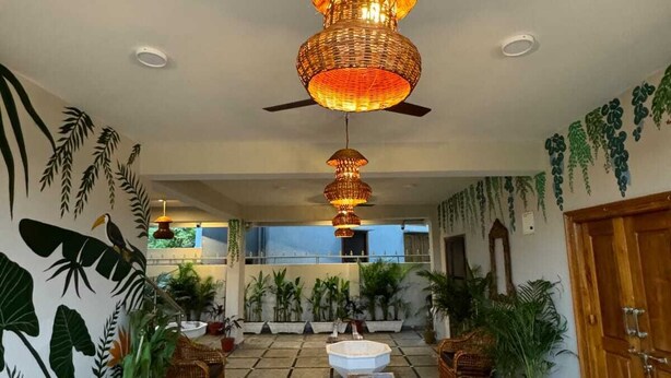 A spacious lobby with a tiled floor, wicker furniture, and hanging plants. - HOTEL URBAN SLEEP (Hyderabad)