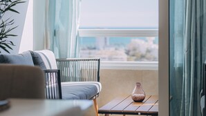 Un balcón con vistas al mar, un sofá, una mesa con un florero y una planta.