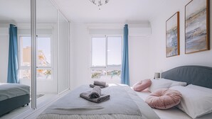 Un dormitorio moderno con una cama grande, vistas al balc ón y un paisaje urbano visible a través de la ventana.