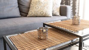 A modern living room with a grey sofa, patterned cushions, and two metal tables with woven placemats. - Stylish Seaview Terrace Retreat  REF002 (Torremolinos)