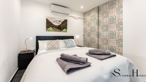 A hotel room with a bed, a nightstand, an air conditioning unit, a painting, and patterned curtains. - Stylish Seaview Terrace Retreat  REF002 (Torremolinos)