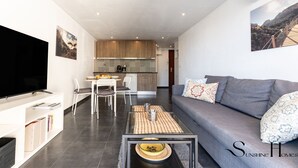 A modern living room with a grey sofa, a flat-screen TV, and a dining area with a table and chairs. - Stylish Seaview Terrace Retreat  REF002 (Torremolinos)