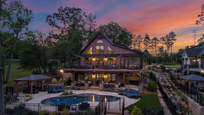 A two-story house with a large deck, a swimming pool, and a stone retaining wall.