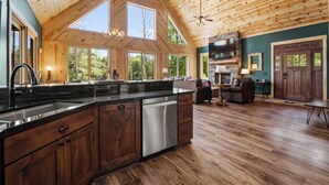 A spacious kitchen with a large island, wooden ceiling, and large windows. - Lakefront w/ Pool, Hot Tub, Theater, Sleeps 20+ | Black Bear Lodge by AvantStay (Sherrills Ford)