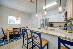 A modern kitchen with white cabinets, a granite countertop, and blue chairs.
